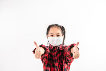 Happy Positive cute Asian little toddler kid girl wearing face mask showing thumbs up for good Stay at home due to the Coronavirus pandemic. Social distancing. New normal idea. White background space