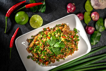 Pork belly mixing in salt and chili with many herbs. A delicious recipe from Asia and spices ingredients on dark black wooden table background, Thai food, Asian foods, Thailand restaurant menu