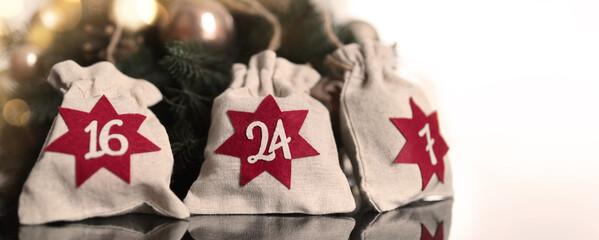 Advent calendar. Christmas bags with gifts on the background of a Christmas wreath and beautiful bokeh.Copy space for text