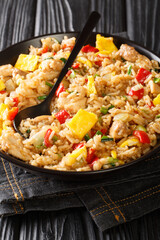 Arroz Chaufa is Peruvian Chinese fried rice consists of rice, red bell peppers, onions, garlic, soy sauce, scrambled eggs and chicken close up in the bowl on the table. Vertical