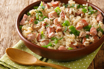Brazilian rice with meat, peppers and herbs close-up in a bowl on a wooden table. horizontal