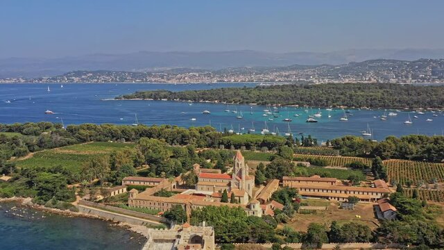 Cannes France Aerial v22 cinematic dolly in shot, drone flying over island of saint honorat and the cistercian abbey overlooking at sailboats cruising on mediterranean sea during summer - July 2021