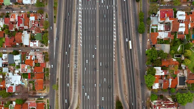 4K vertical aerial view from above of many vehicles crossing the Pan-American highway where many villas can be seen around it. Located in Buenos Aires, Argentina.