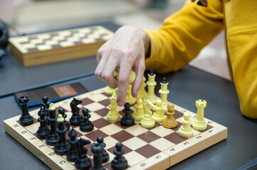 Man holds a chess piece with his hand. Chess board. Chess tournament