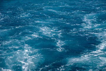 Fototapeta na wymiar Rough deep turquoise and blue sea with white foam texture background