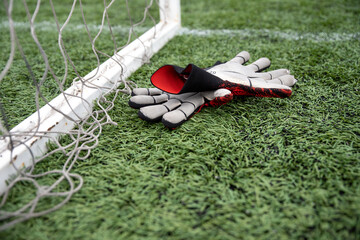 Top view of goalkeeper gloves lying on soccer pitch