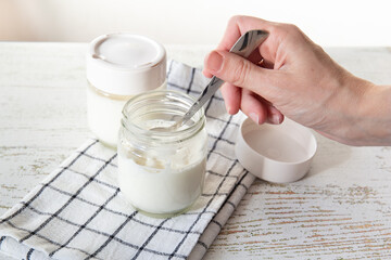 A woman's hand tastes freshly made yogurt with a spoon.