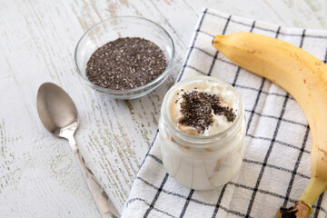 A jar of homemade yogurt filled with banana and chia seeds. Healthy food concept.