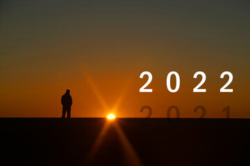 Silhouette of End of year 2021 and Countdown to New year 2022 letters on the rooftop with sunset light, Concept new success , goal , target start 2022  