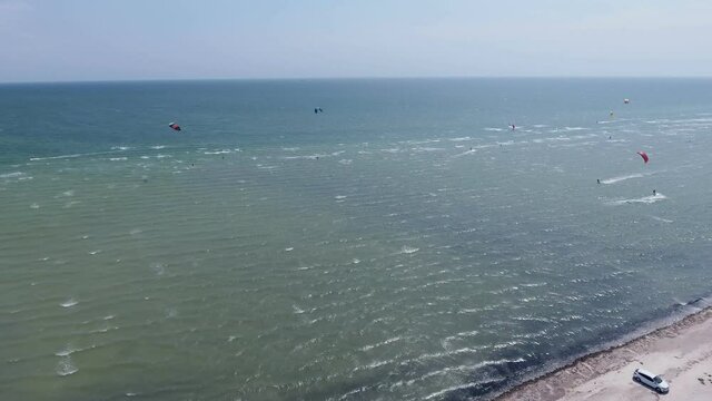 Aerial shot of the Black Sea beach with tourists and several parashutes in summer