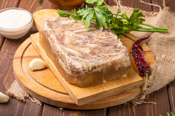 Chicken meat jelly with garlic, mustard and horseradish on a wooden table. A classic Russian dish.
