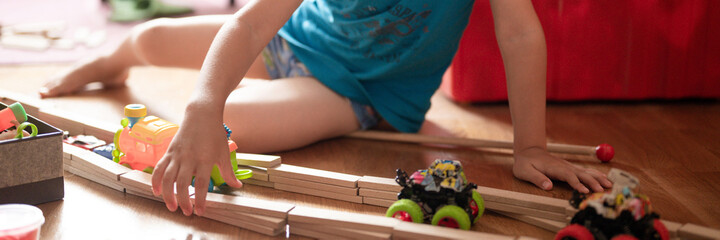 cute little candid five year old kid boy playing at home with children's toys cars and the wooden...