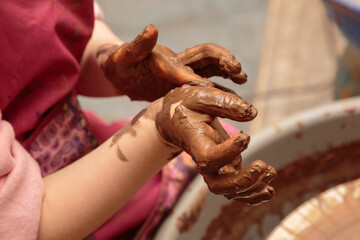 Children's hands are smeared by clay.