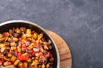 Fried potatoes with meat and onions in a pan, close-up, free space.