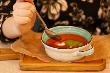 A woman is eating tomato soup
