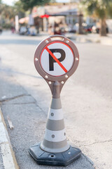 cone warning about a parking ban of automobile and cars. traffic safety sign on city street road....