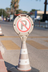cone warning about a parking ban of automobile and cars. traffic safety sign on city street road....