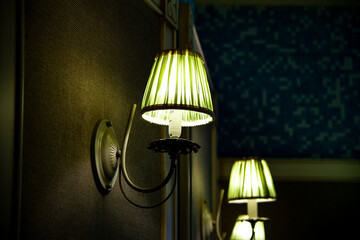 lamps on the wall. green sconces. two lamps with plafonds on a dark wall