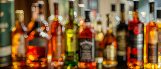 Beautiful bokeh from a row of alcoholic bottles in backlight. - obrazy, fototapety, plakaty