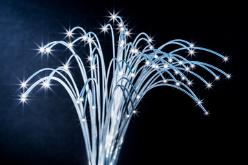 Bundle of optical fibers with lights in the ends. Dark blue background.