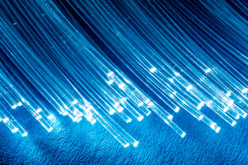 Bundle of optical fibers with lights in the ends. Blue background.