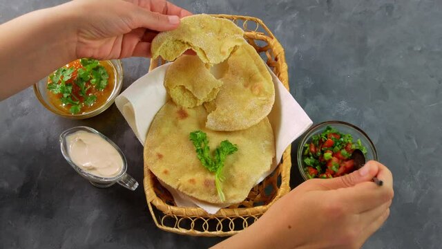 Homemade corn flatbread female hand cilantro greens tomato salsa. Handmade mexican tortillas vegetable salad Traditional Indian Punjabi Makki ki roti bread plate 4K Wheat flour dough authentic cuisine