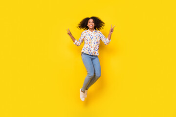 Fototapeta na wymiar Full size photo of pretty young wavy hairdo lady jump show v-sign wear blouse jeans sneakers isolated on yellow background