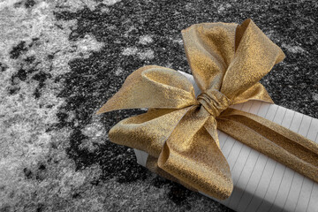 A gift box decorated with a bow. Golden-copper gamma. Icy surface. Concept: Christmas, New year,...