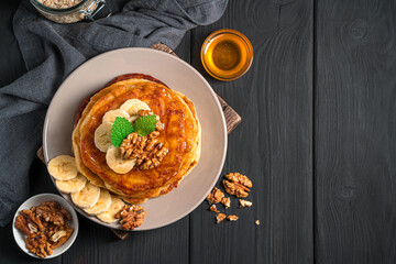 Pancakes with honey and nuts on a black background.