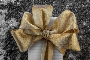 A gift box decorated with a bow. Golden-copper gamma. Icy surface. Concept: Christmas, New year,...