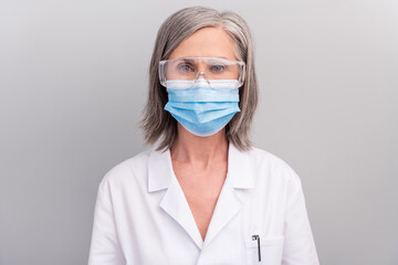 Photo of confident pretty senior woman doc dressed white uniform glasses facial mask isolated grey color background