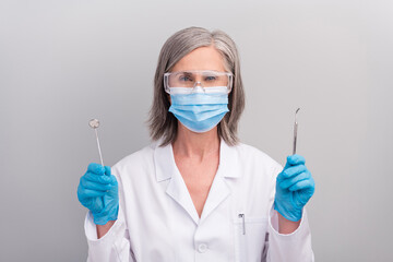 Photo of attentive confident woman doc dressed white uniform glasses face mask holding dentistry equipment isolated grey color background