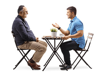 Young man sitting at a cafe and talking to a mature man