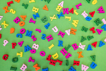 Fototapeta na wymiar colored English letters are randomly scattered on a green background.