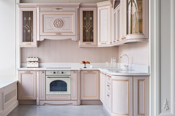 classic kitchen with oak facades in pink with carved elements and a white stone countertop