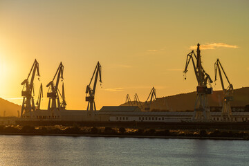 Group of shipyard cranes against yellow sky at sunset in Ferrol, Galicia, Spain