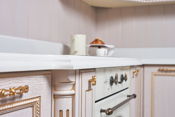 classic kitchen with oak facades in pink with carved elements and a white stone countertop