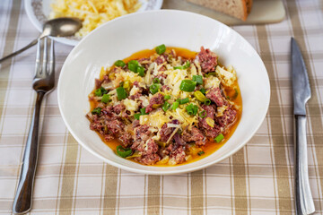 Minced beef meat with onion and leek, grated cheese, cutlery.