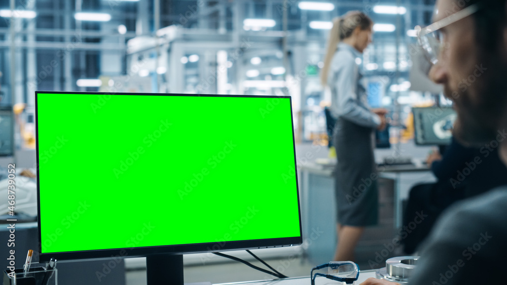 Poster car factory office: caucasian male automotive engineer sitting at his desk working on green screen c
