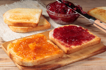 Toasts with red and orange jam on wooden board. Selective focus.