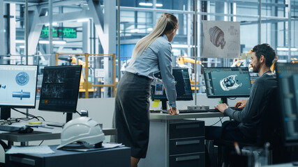Car Factory Office: Project Manager Talks to Engineer Working on Computer, uses CAD Software with...