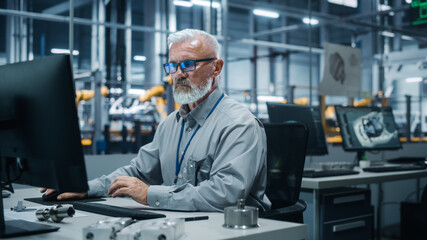 Car Factory Office: Portrait of Male Engineer Working on Computer. Automated Robot Arm Assembly...
