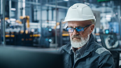 Car Factory Office: Portrait of Male Engineer Working on Computer. Automated Robot Arm Assembly...