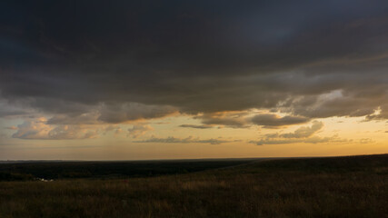 Evening clouds in a hilly terrain, panoramic landscape.