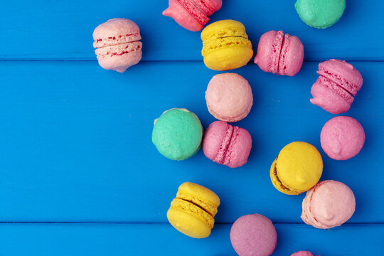 Pile of delicious colorful macarons on blue background