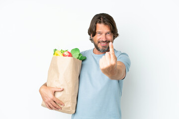 Senior dutch man holding grocery shopping bag over isolated background doing coming gesture