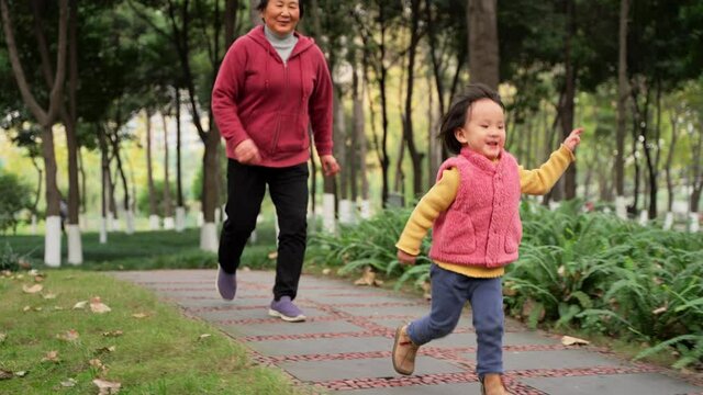 happy little asian girl playing with her grandmother outdoor in the autumn park active senior woman running after her granddaughter outdoor healthy relax family lifestyles old and young 4k footage