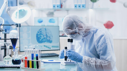 Scientist researcher doctor analyzing blood slide using medical microscope developing vaccine...