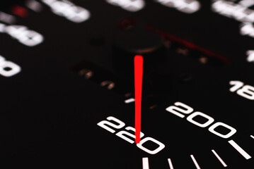 Car speedometer. Auto car speedometer shows 220 km h or miles.Closeup shot,dark black background.Automobile dangerous speed concept