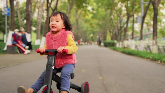 Slow motion one little asian girl ridding on her bike at the autumn park active child lifestyles outdoor 4k footage